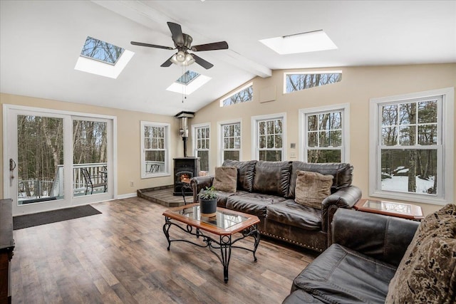 living room featuring wood finished floors, baseboards, a wood stove, vaulted ceiling with beams, and ceiling fan