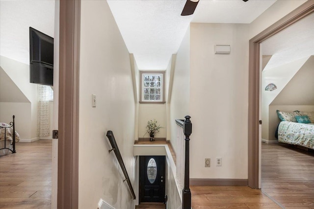 hall with baseboards, an upstairs landing, and wood finished floors