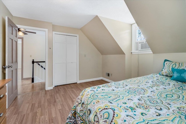 bedroom with cooling unit, baseboards, wood finished floors, and vaulted ceiling