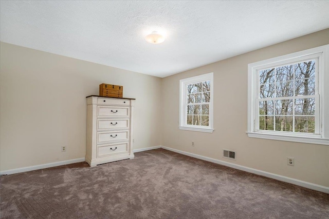 unfurnished bedroom with visible vents, multiple windows, and carpet