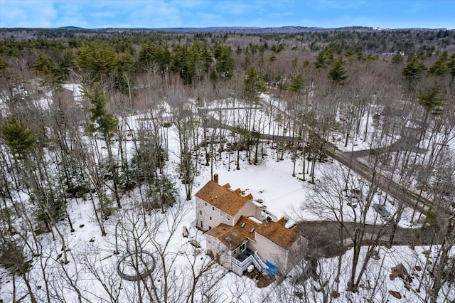 snowy aerial view featuring a wooded view