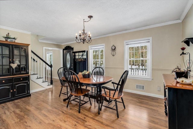 dining room with visible vents, baseboards, stairway, ornamental molding, and wood finished floors