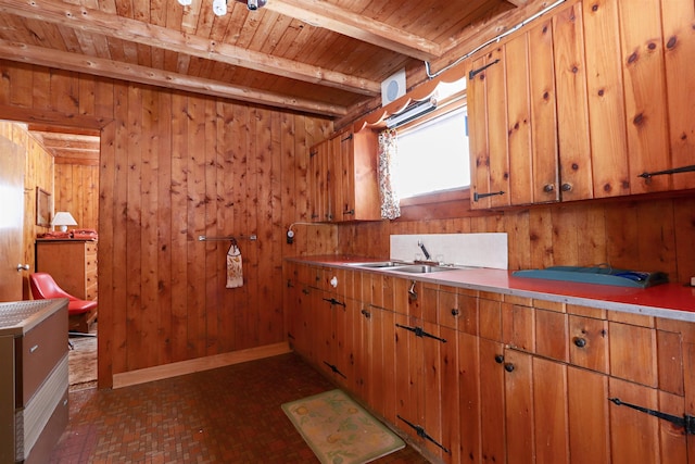 kitchen with beam ceiling, a sink, wood walls, brick floor, and wood ceiling