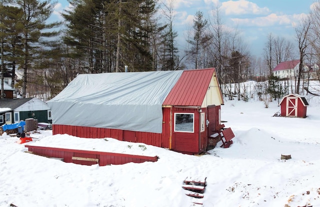 snow covered structure featuring an outbuilding