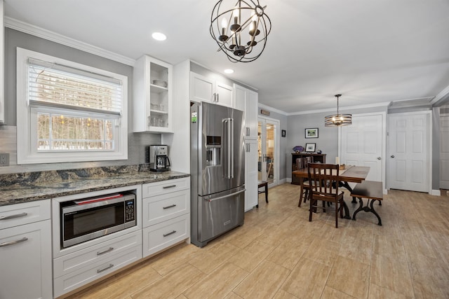 kitchen featuring stainless steel appliances, white cabinets, glass insert cabinets, crown molding, and a notable chandelier