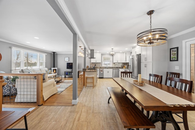 dining room with recessed lighting, light wood-style floors, ornamental molding, and a wood stove