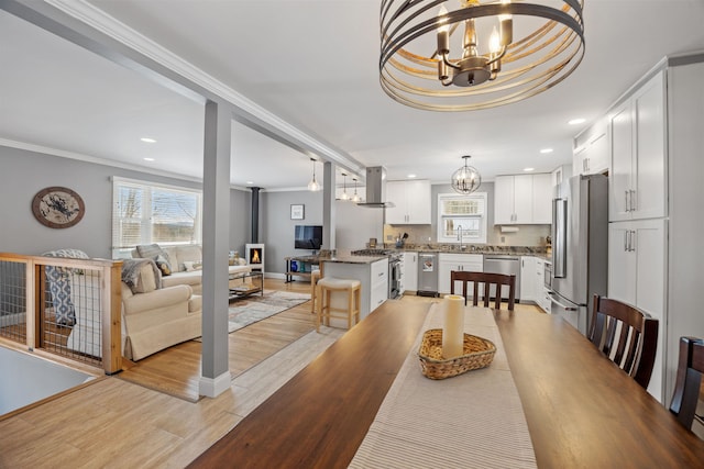 dining area featuring a healthy amount of sunlight, light wood finished floors, and a chandelier