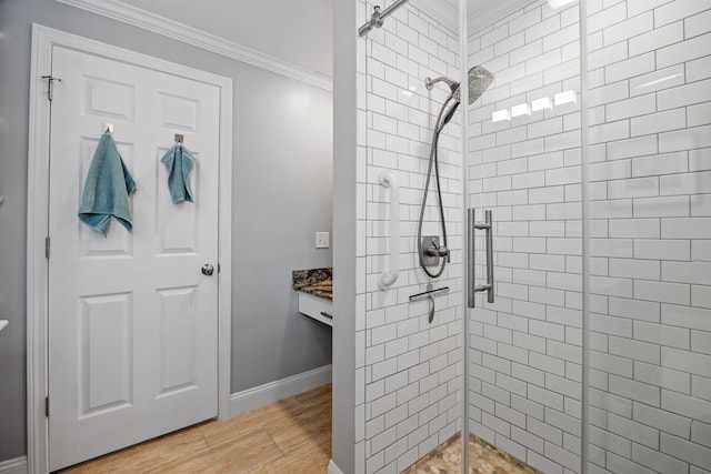 bathroom featuring a shower stall, wood finished floors, baseboards, and ornamental molding