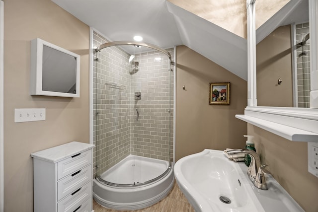 bathroom with a sink, lofted ceiling, and a stall shower