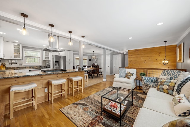 living room with crown molding, recessed lighting, light wood-type flooring, and a chandelier