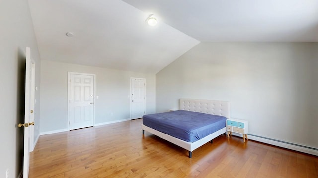 bedroom featuring a baseboard radiator, baseboards, lofted ceiling, and wood finished floors