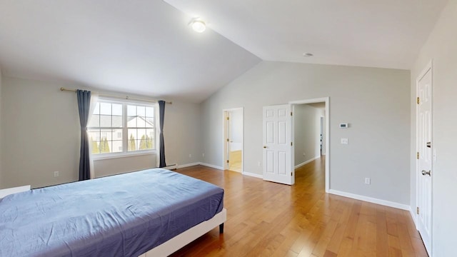 bedroom featuring baseboards, wood finished floors, and vaulted ceiling