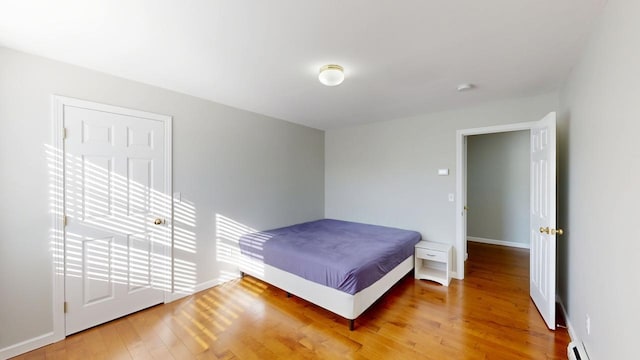 bedroom featuring baseboard heating, light wood-style flooring, and baseboards