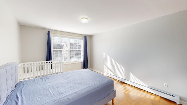 bedroom with baseboard heating, baseboards, and wood finished floors