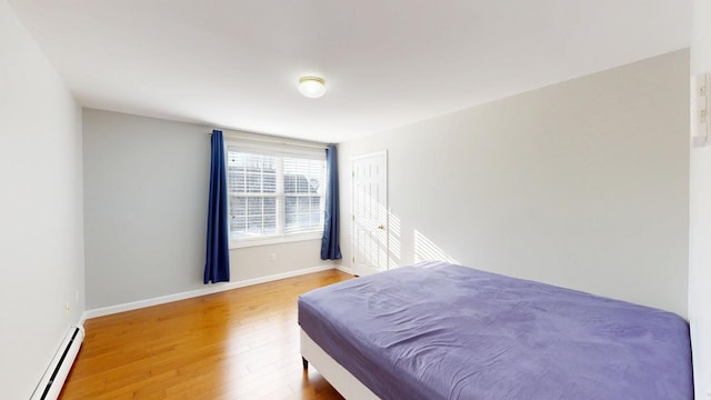 bedroom with wood finished floors, baseboards, and baseboard heating