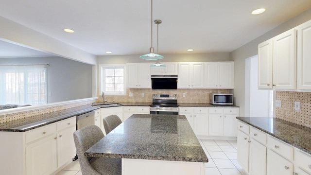 kitchen featuring dark stone counters, light tile patterned flooring, a sink, appliances with stainless steel finishes, and backsplash