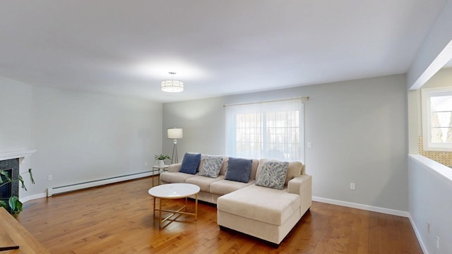 living area featuring baseboard heating, hardwood / wood-style flooring, baseboards, and a premium fireplace