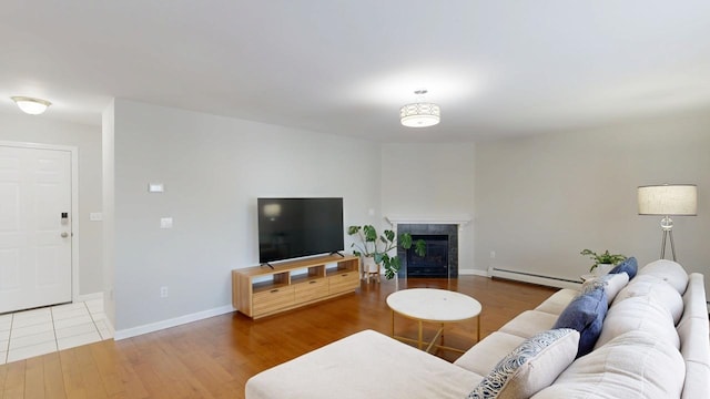 living area featuring wood finished floors, baseboards, baseboard heating, and a tile fireplace