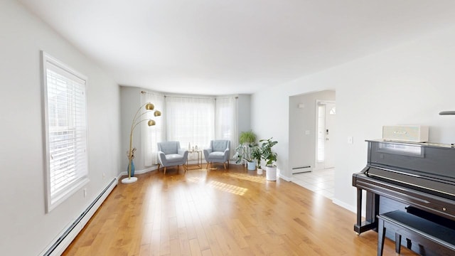 living area featuring a wealth of natural light, light wood-type flooring, a baseboard heating unit, and a baseboard radiator