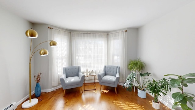 sitting room featuring baseboards, wood-type flooring, and a baseboard radiator