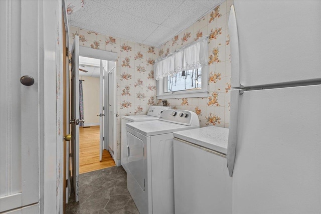 clothes washing area featuring laundry area, independent washer and dryer, and wallpapered walls