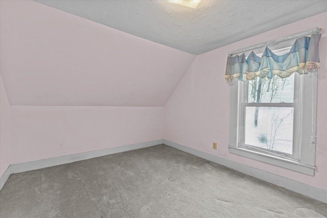 bonus room with carpet flooring, a textured ceiling, baseboards, and vaulted ceiling