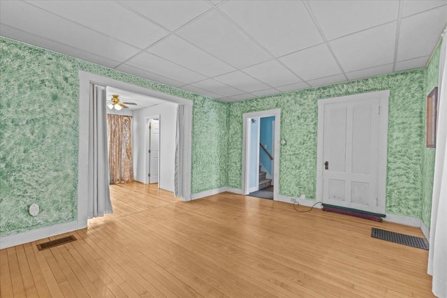 unfurnished room with visible vents, wallpapered walls, a paneled ceiling, and hardwood / wood-style floors