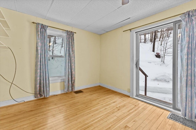 empty room with visible vents, baseboards, and wood-type flooring