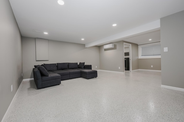 living area featuring an AC wall unit, recessed lighting, speckled floor, and baseboards