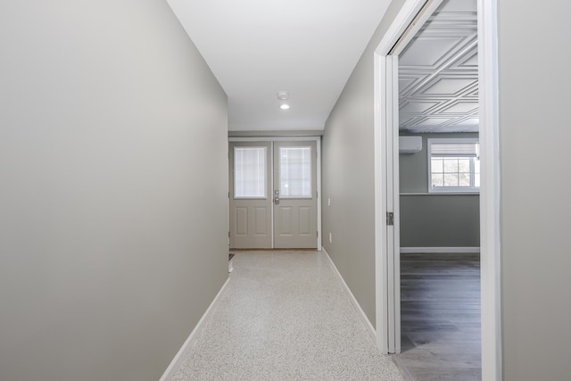 hall with an AC wall unit and baseboards