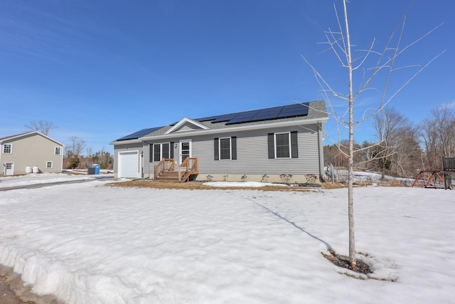 ranch-style house with a garage and roof mounted solar panels