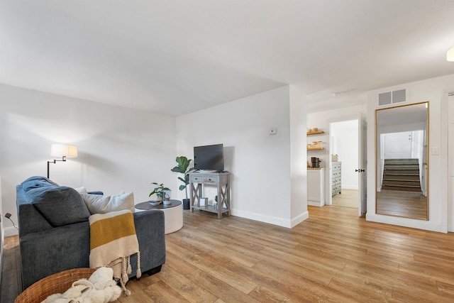 living area with visible vents, baseboards, and light wood finished floors