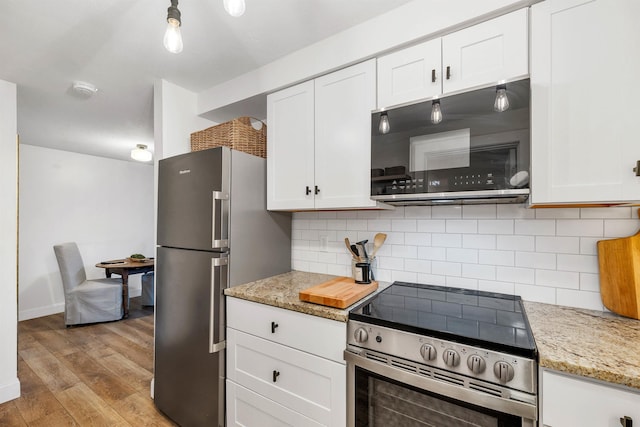 kitchen featuring light wood-type flooring, tasteful backsplash, stainless steel appliances, white cabinets, and light stone countertops