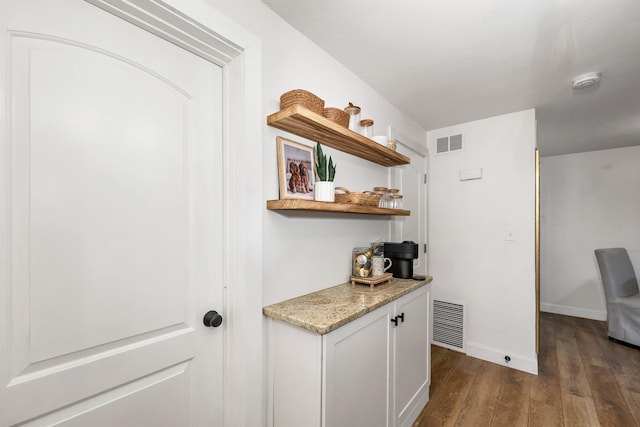 interior space featuring visible vents, baseboards, and dark wood finished floors