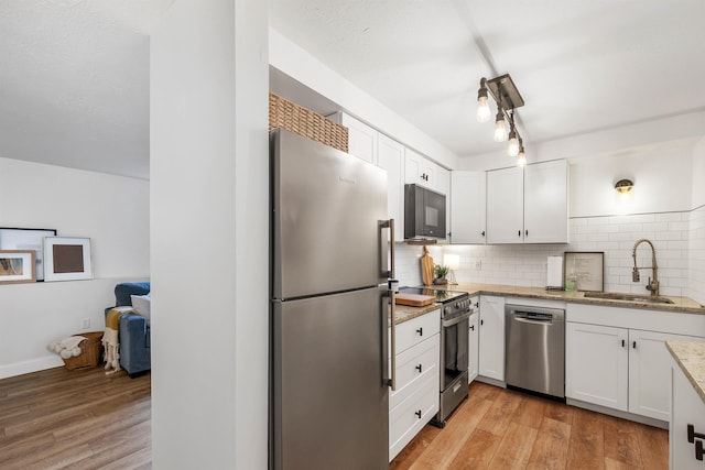 kitchen with a sink, white cabinetry, backsplash, and stainless steel appliances