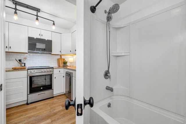 kitchen with light wood-style flooring, electric stove, black microwave, white cabinetry, and backsplash