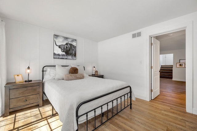 bedroom featuring visible vents, baseboards, and wood finished floors