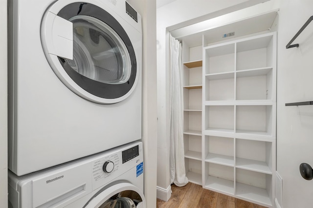 washroom with laundry area, stacked washing maching and dryer, and wood finished floors