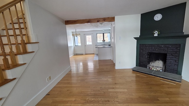 corridor with visible vents, baseboards, stairway, light wood-style flooring, and a baseboard radiator