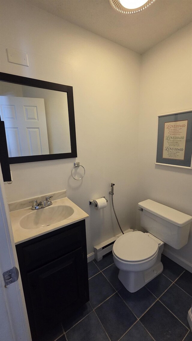 half bathroom featuring tile patterned flooring, a baseboard heating unit, baseboards, toilet, and vanity