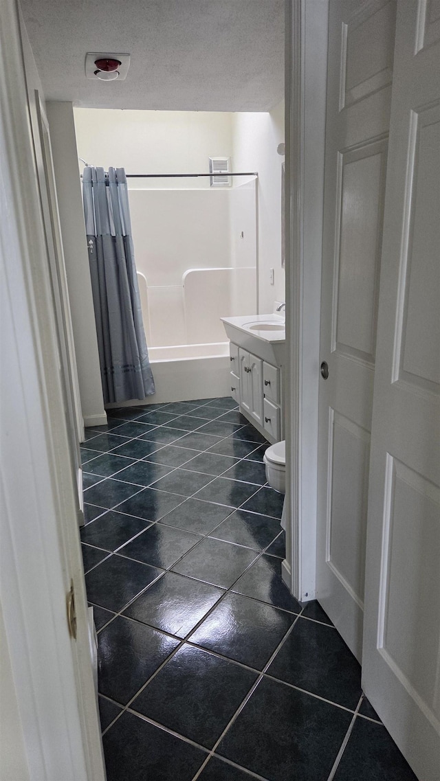 bathroom with toilet, vanity, shower / bath combo, tile patterned floors, and a textured ceiling