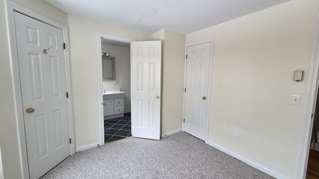 unfurnished bedroom with carpet flooring, connected bathroom, and baseboards