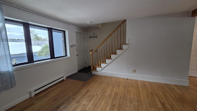 entrance foyer featuring light wood finished floors, baseboard heating, stairs, and baseboards