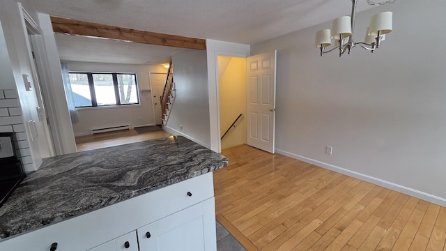 kitchen featuring a baseboard heating unit, baseboards, light wood-style flooring, and white cabinetry