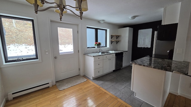 kitchen featuring a sink, black dishwasher, light wood-style floors, white cabinets, and baseboard heating