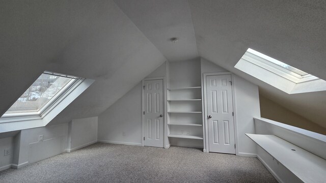 additional living space with baseboards, vaulted ceiling with skylight, and carpet