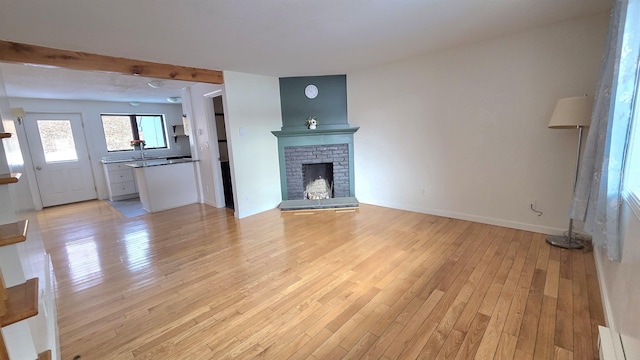 unfurnished living room with a fireplace, light wood-type flooring, and baseboards