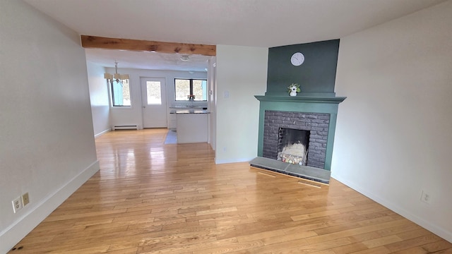 unfurnished living room with baseboard heating, baseboards, light wood-style floors, and a brick fireplace