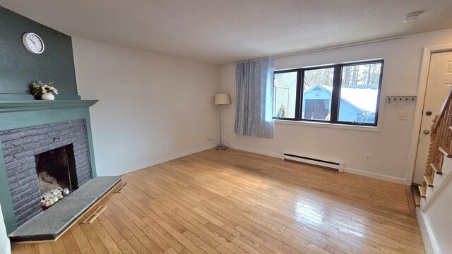 unfurnished living room with a baseboard heating unit, stairs, a fireplace, and wood-type flooring