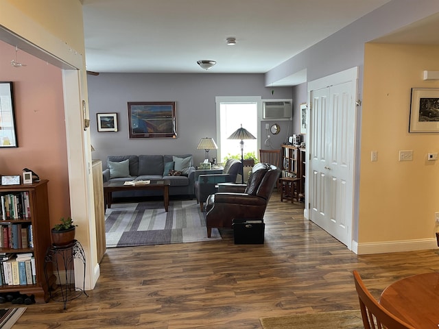 living room with an AC wall unit, dark wood-style floors, and baseboards